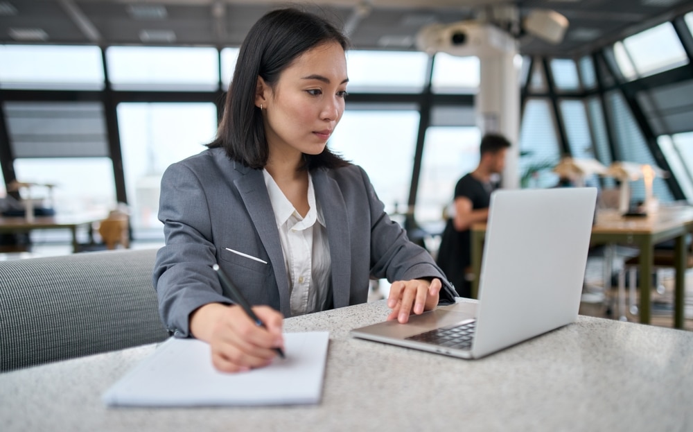 Young female professional working on a laption in a contemporary office setting.